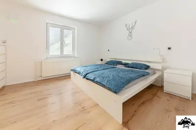 a white bedroom with a bed and a window at Brlog in Zgornje Gorje