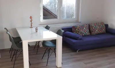 a living room with a white table and a blue couch at Apartmaji Pika in Cerklje na Gorenjskem