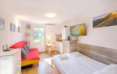 a living room with a red couch and a table at Studio Southwest 3 with AirCon & FREE Parking in Ljubljana
