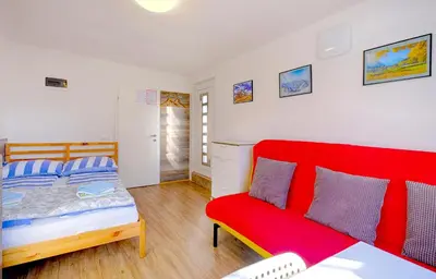 a bedroom with a red bed and a red couch at Studio Southwest 3 with AirCon & FREE Parking in Ljubljana
