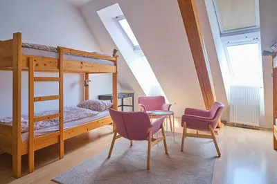 a bedroom with bunk beds and chairs and a table at Samostan Mekinje in Kamnik