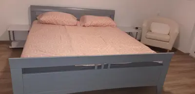 a bed with a gray frame and a chair in a room at Apatmaji Pika 2 in Cerklje na Gorenjskem