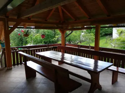 a wooden bench on a porch with a table at Apatmaji Pika 2 in Cerklje na Gorenjskem