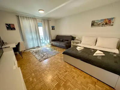 a bedroom with a bed and a living room with a couch at Clara Ljubljana Apartment in Ljubljana