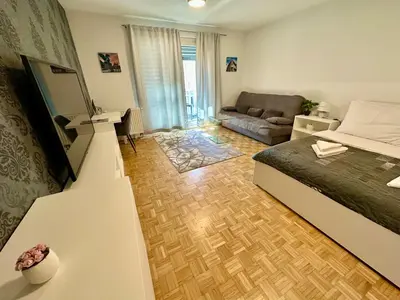 a bedroom with a bed and a living room with a couch at Clara Ljubljana Apartment in Ljubljana