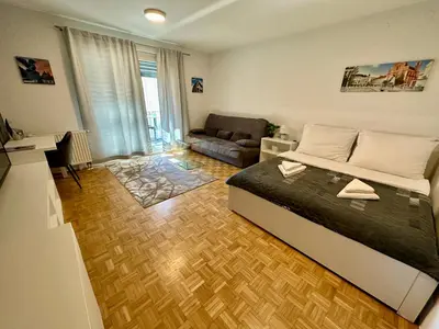 a bedroom with a bed and a living room at Clara Ljubljana Apartment in Ljubljana