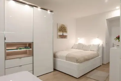 a white bedroom with a bed and a mirror at Studio Apartment Gea Tour As Ljubljana in Ljubljana