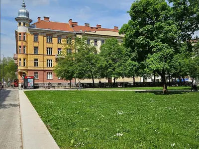 a large yellow building with a tree in a park at Studio Apartment Gea Tour As Ljubljana in Ljubljana