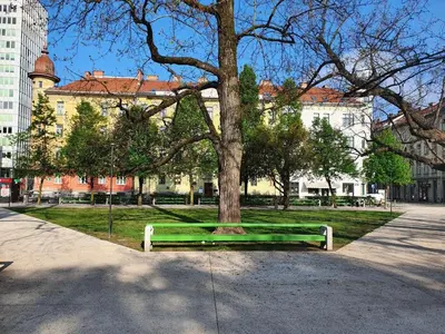 a park with a green bench next to a tree at Studio Apartment Gea Tour As Ljubljana in Ljubljana