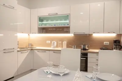 a kitchen with white cabinets and a table with wine glasses at Studio Apartment Gea Tour As Ljubljana in Ljubljana