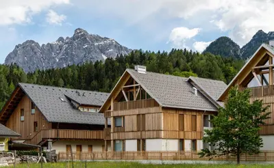 a row of wooden houses with mountains in the background at Apartment Špica - Private parking in Kranjska Gora