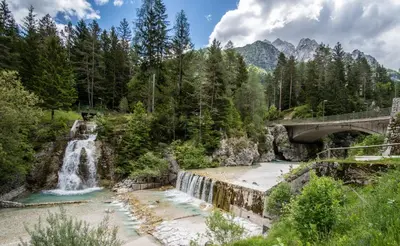a waterfall in the mountains with a bridge at Apartment Špica - Private parking in Kranjska Gora