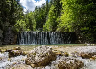 a waterfall in the middle of a river with rocks at Apartment Špica - Private parking in Kranjska Gora