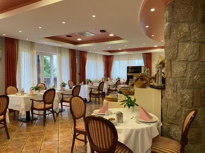 a restaurant with tables and chairs and a stone wall at Hotel Grahor Depandance in Sežana