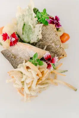 a sandwich with flowers on a white plate at Hotel Grahor Depandance in Sežana
