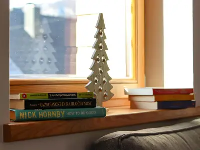 a stack of books on a window sill with a christmas tree at Bohinj - Old Village House in Bohinj