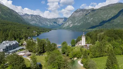 an aerial view of a resort with a lake and mountains at Bohinj - Old Village House in Bohinj
