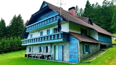 a blue and white house on a green field at Apartma Bellevue Rogla in Vitanje