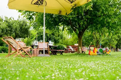 a yellow umbrella sitting in the grass in a park at APARTMA RANČ LUŽE in Kranj