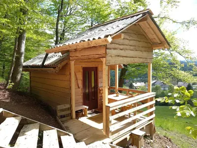 a small wooden dog house with a porch at Glamping Laze in Gorenja Vas