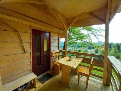 a porch of a cabin with a wooden table and chairs at Glamping Laze in Gorenja Vas