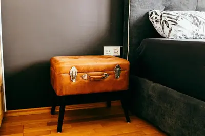 a brown suitcase sitting on a stool next to a bed at HERMES APARTMENT & 2 free garage secured parkings in Ljubljana