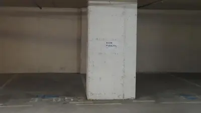 a white wall in a parking garage with a sign on it at HERMES APARTMENT & 2 free garage secured parkings in Ljubljana