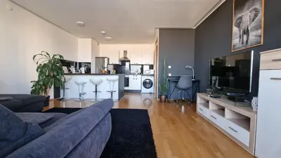 a living room with a blue couch and a kitchen at HERMES APARTMENT & 2 free garage secured parkings in Ljubljana