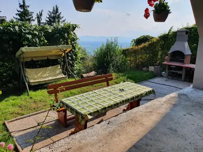 a picnic table and bench with a view of the ocean at Veronica's place in the mountains in Cerklje na Gorenjskem