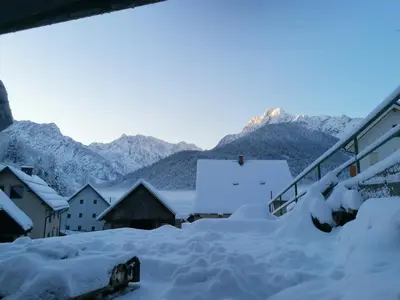 a village covered in snow with mountains in the background at Apartment Erlah in Rateče