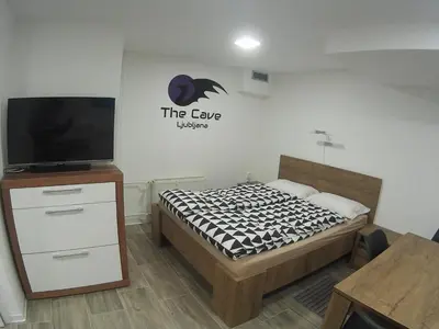 a small bedroom with a bed and a tv at The Cave in Ljubljana