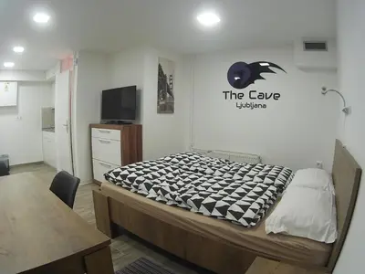 a room with a bed and a table and a tv at The Cave in Ljubljana