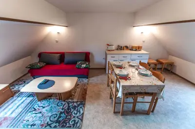 a living room with a table and a red couch at Apartments Jože Pekovec in Bohinj