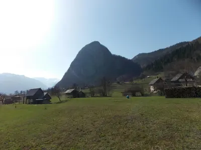 a green field with houses and mountains in the background at Apartments Jože Pekovec in Bohinj