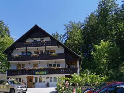 a building with a balcony with flowers on it at Accommodation Destina, LAKE BOHINJ in Bohinj