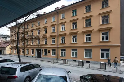 a large building with cars parked in front of it at Stay in pub KAMERA KLUB apatment-city center in Ljubljana