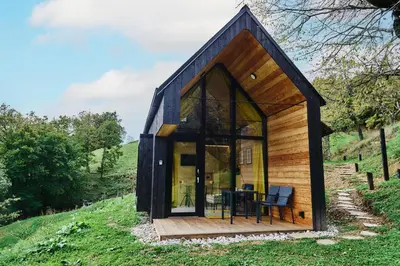 a small house with a black roof on a hill at Tri Vile Estate, a piece of paradise in Kozjansko in Podčetrtek
