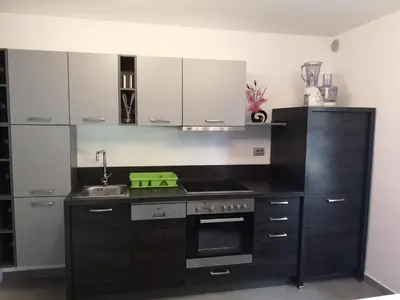 a kitchen with black cabinets and a stove top oven at APP Vanja 6170 in Čatež ob Savi