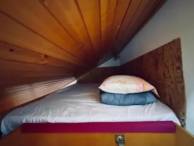 a bed in a room with a wooden ceiling at Apartma Snežinka in Kranjska Gora