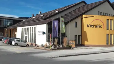a yellow and white building with cars parked in a parking lot at Apartma Snežinka in Kranjska Gora