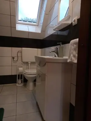 a bathroom with a sink and a toilet with a window at ODAI in Bovec