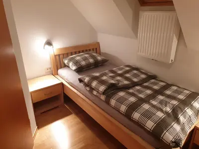 a small bedroom with a bed and a night stand at Apartma DA-LI SPORTS -ROGLA in Zreče