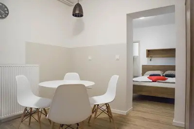a white table and chairs in a room with a bed at Jantar Apartmaji in Novo Mesto