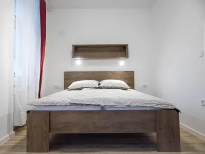 a bedroom with a bed with a wooden headboard at Jantar Apartmaji in Novo Mesto