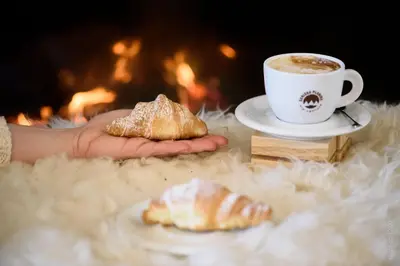 a person holding a cup of coffee and a pastry at Guesthouse Lajnar in Zgornja Sorica