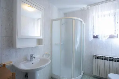 a white bathroom with a sink and a shower at Apartment Melody Bled in Bled