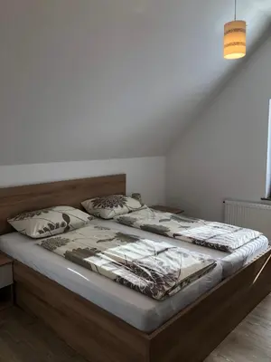 a bedroom with a large bed with a wooden headboard at Apartmaji Kramar Rateče in Kranjska Gora