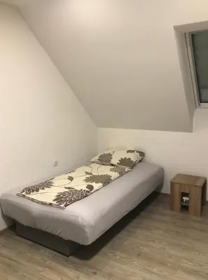 a bed in a corner of a room with a table at Apartmaji Kramar Rateče in Kranjska Gora