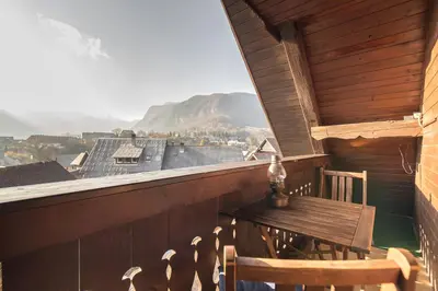 a wooden balcony with a wooden table and chairs at Apartmaji Katja in Bohinj