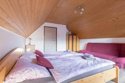 a large bed in a room with a purple couch at Apartmaji Katja in Bohinj